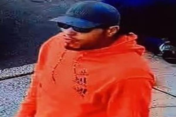 The suspect in the broad-daylight assault on a 65-year-old man, seen wearing sunglasses and an orange hoodie. 